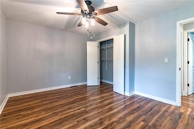 unfurnished bedroom featuring dark wood-style flooring, ceiling fan, baseboards, visible vents, and a closet