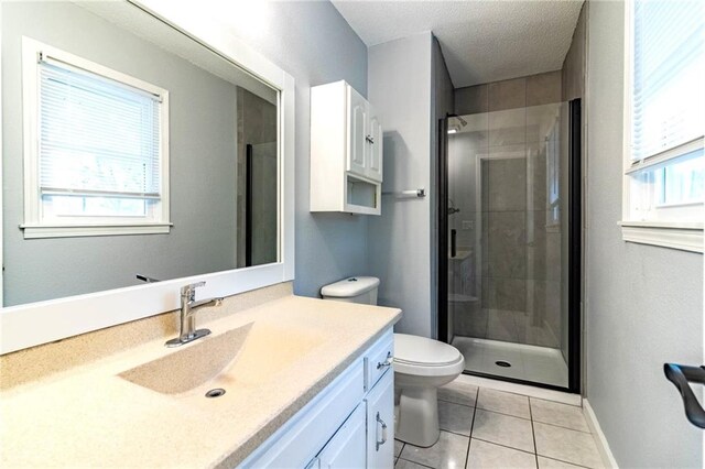 bathroom featuring tile patterned flooring, vanity, toilet, baseboards, and a stall shower