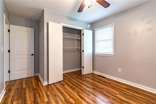 unfurnished bedroom with ceiling fan, baseboards, wood finished floors, visible vents, and a closet