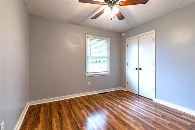 unfurnished bedroom featuring a closet, wood finished floors, baseboards, ceiling fan, and a textured ceiling