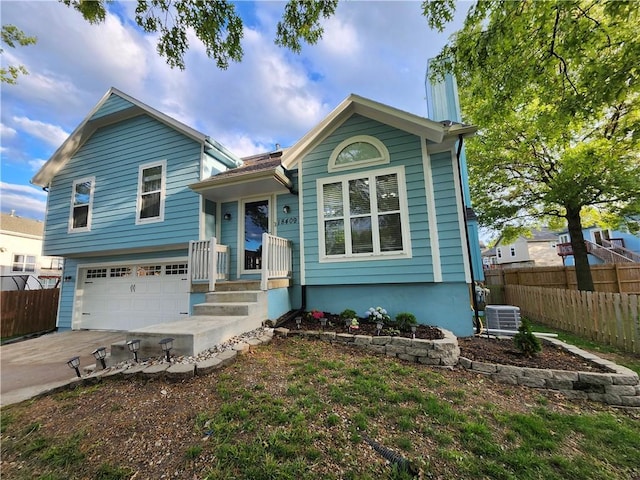 split level home with fence, cooling unit, concrete driveway, and a garage