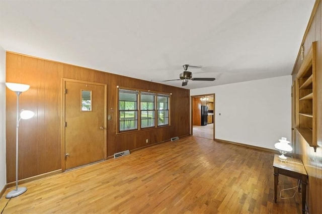 26335 W 321st Ter, Paola, KS 66071 - unfurnished living room featuring light wood-type flooring, a ceiling fan, and wooden walls