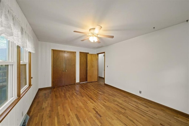 26335 W 321st Ter, Paola, KS 66071 - unfurnished bedroom featuring multiple closets, wood finished floors, and a ceiling fan