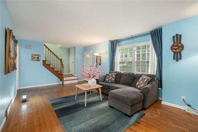 living room with visible vents, baseboards, stairs, and wood finished floors