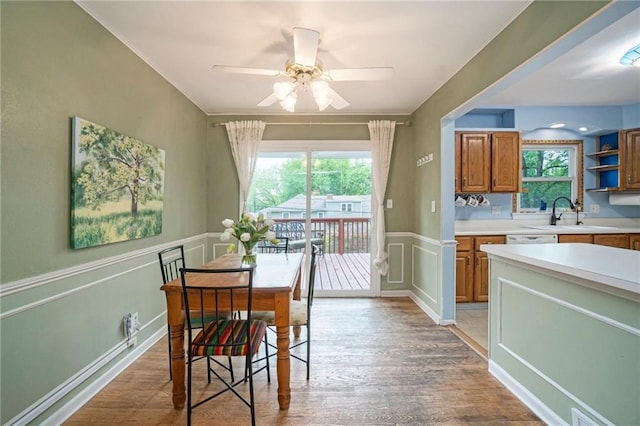 dining space with a wainscoted wall, light wood-type flooring, and a wealth of natural light