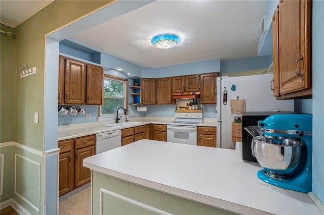 kitchen featuring a sink, white appliances, light countertops, a peninsula, and under cabinet range hood