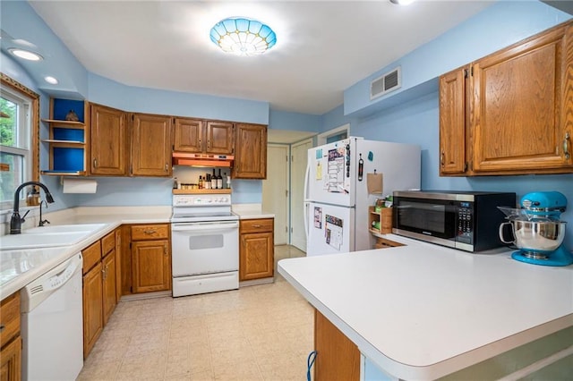 kitchen featuring visible vents, brown cabinetry, white appliances, light countertops, and a sink