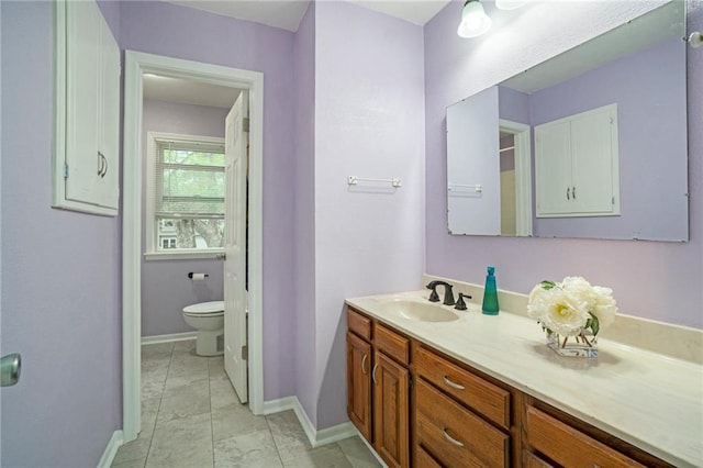 bathroom with toilet, baseboards, and vanity