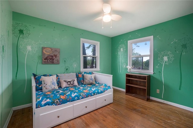 bedroom featuring a ceiling fan, baseboards, multiple windows, and wood finished floors