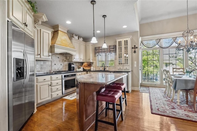 10522 N Garfield Ave, Kansas City, MO 64155 - kitchen with appliances with stainless steel finishes, cream cabinets, a sink, wood finished floors, and ornamental molding