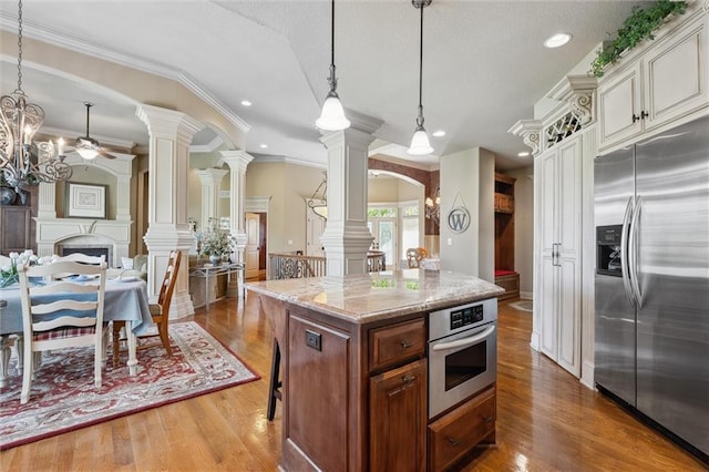 10522 N Garfield Ave, Kansas City, MO 64155 - kitchen featuring stainless steel appliances, decorative columns, ceiling fan, light stone counters, and wood finished floors