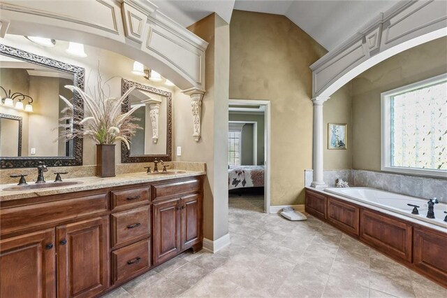 10522 N Garfield Ave, Kansas City, MO 64155 - ensuite bathroom featuring a bath, double vanity, decorative columns, tile patterned flooring, and baseboards