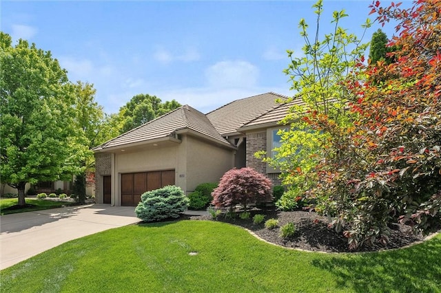 view of front of house featuring a tiled roof, a front yard, driveway, and a garage