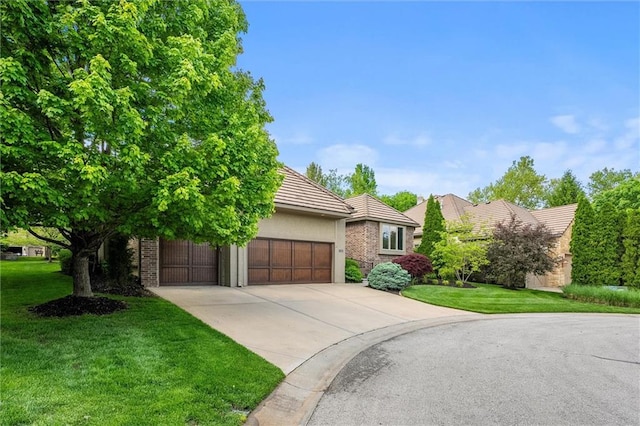 view of front of house featuring a front yard, a tiled roof, driveway, and an attached garage