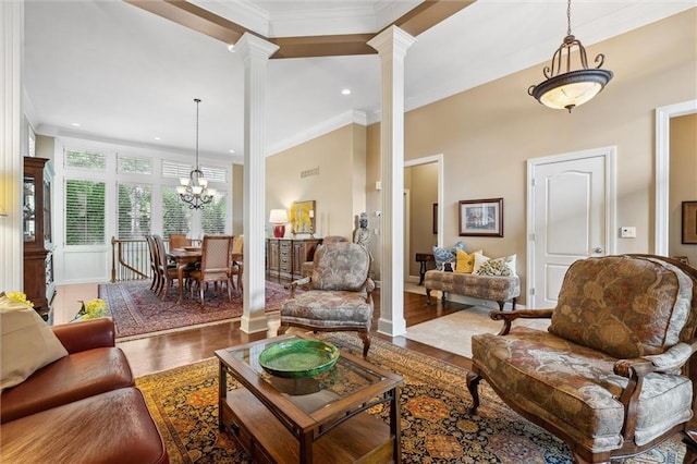 living area with ornate columns, wood finished floors, a chandelier, ornamental molding, and recessed lighting