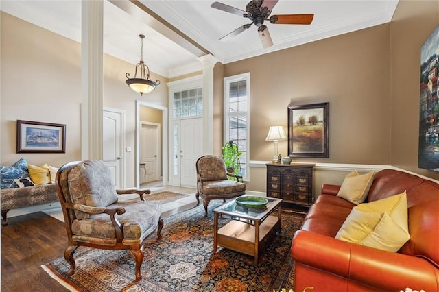 living area featuring ornate columns, crown molding, wood finished floors, and ceiling fan