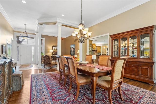 dining space featuring a chandelier, ornamental molding, ornate columns, recessed lighting, and wood finished floors