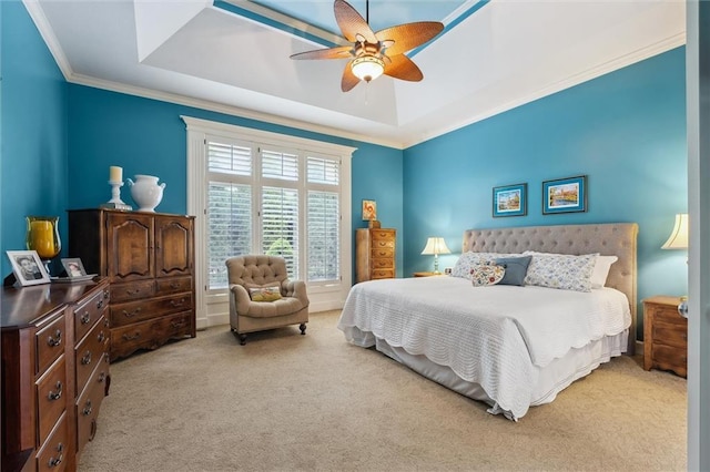carpeted bedroom featuring a raised ceiling, ornamental molding, and a ceiling fan