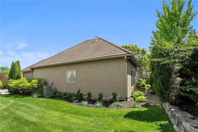 view of side of home with central AC unit, a lawn, and stucco siding