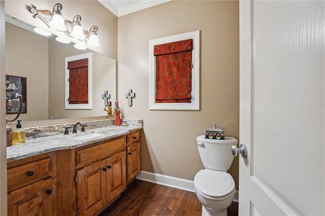 half bath featuring ornamental molding, baseboards, wood finished floors, toilet, and vanity