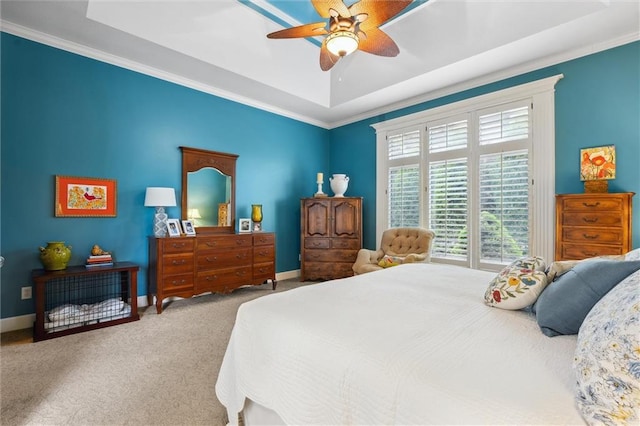 bedroom with carpet floors, ornamental molding, a tray ceiling, a ceiling fan, and baseboards