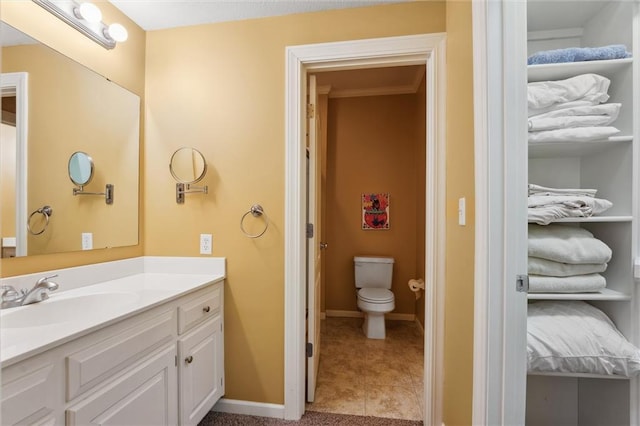 bathroom with toilet, vanity, and baseboards