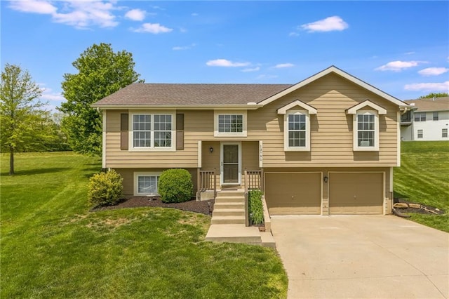 bi-level home with an attached garage, concrete driveway, and a front yard