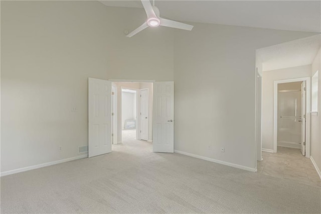 spare room featuring ceiling fan, light colored carpet, baseboards, and high vaulted ceiling