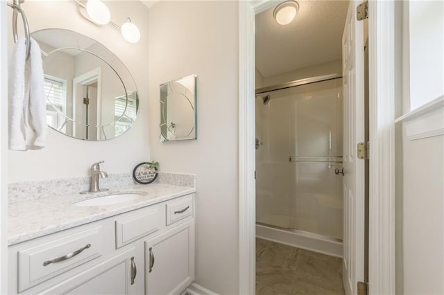 bathroom featuring marble look tile flooring, a shower stall, and vanity