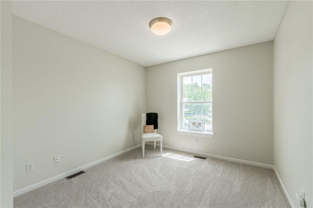 carpeted empty room with baseboards and a textured ceiling