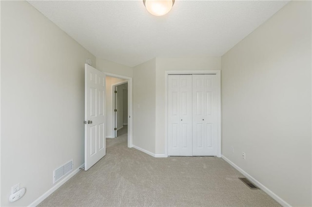 unfurnished bedroom with light colored carpet, baseboards, and a closet