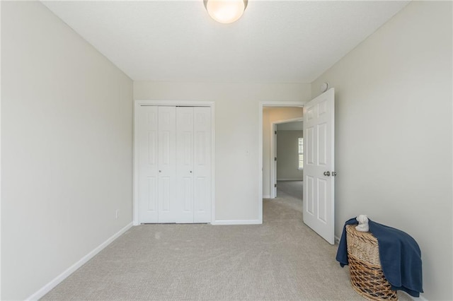 unfurnished bedroom with light colored carpet, baseboards, and a closet