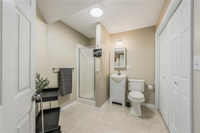 bathroom with a shower stall, toilet, vanity, baseboards, and tile patterned flooring