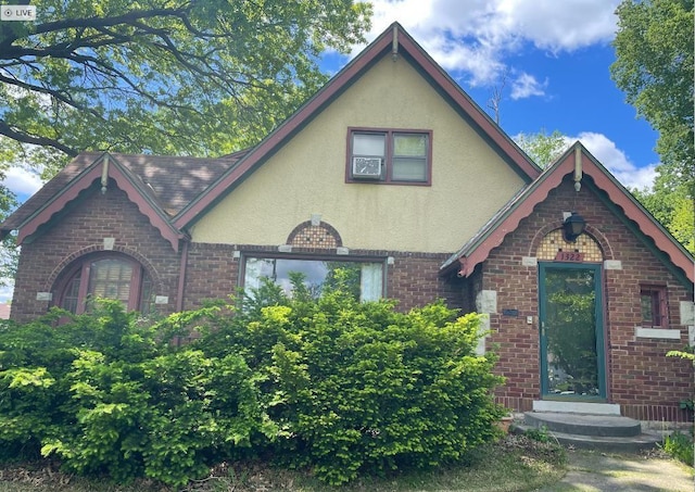 tudor-style house featuring stucco siding and brick siding