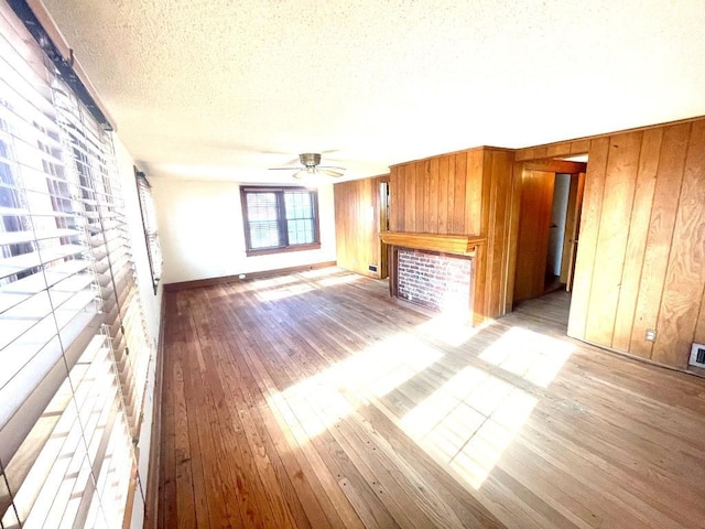 unfurnished living room featuring light wood-type flooring and wooden walls