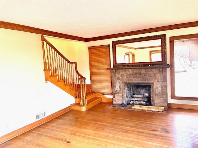 unfurnished living room featuring stairway, ornamental molding, visible vents, and wood finished floors