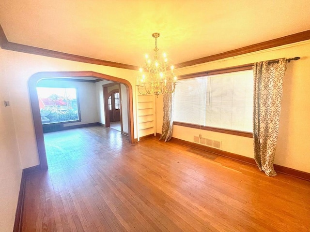 unfurnished dining area with arched walkways, an inviting chandelier, visible vents, and wood finished floors