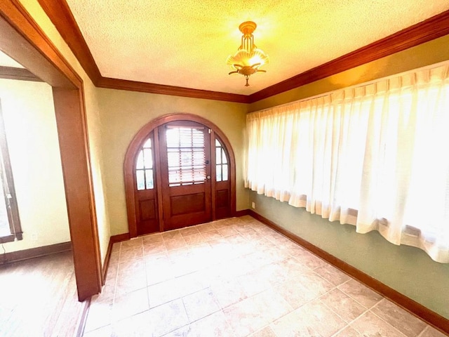 foyer with arched walkways, baseboards, crown molding, and a textured ceiling