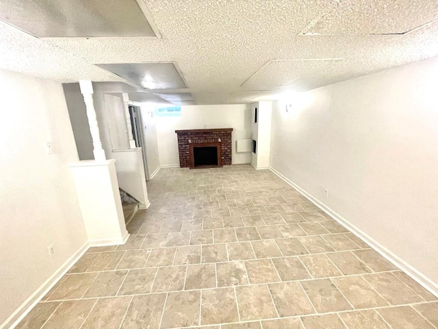 finished below grade area featuring a brick fireplace, baseboards, and stairway