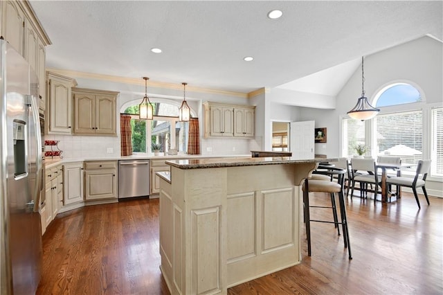 14575 Granada Cir, Leawood, KS 66224 - kitchen featuring appliances with stainless steel finishes, cream cabinetry, plenty of natural light, a center island, and vaulted ceiling