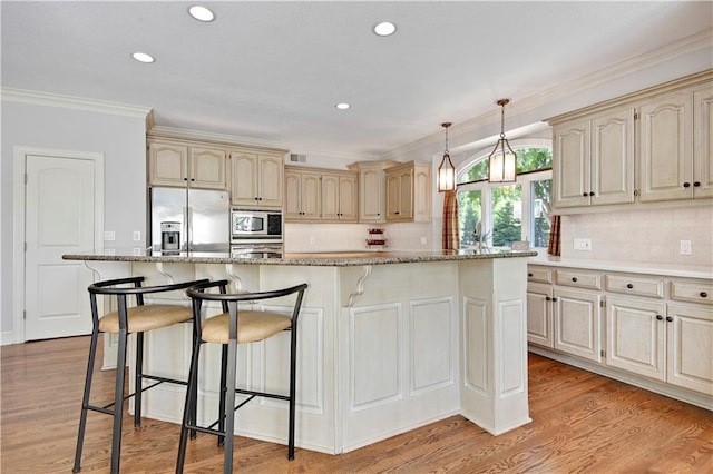 14575 Granada Cir, Leawood, KS 66224 - kitchen with appliances with stainless steel finishes, cream cabinets, a kitchen breakfast bar, light wood-style floors, and recessed lighting