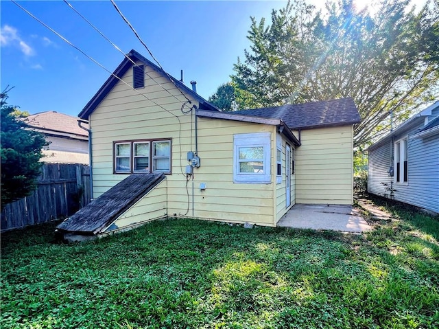 rear view of house featuring fence and a lawn