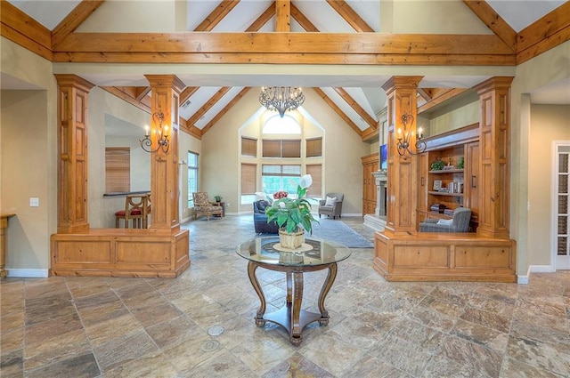 11629 Tomahawk Creek Pkwy Unit G, Leawood, KS 66211 - living room with stone tile flooring, high vaulted ceiling, decorative columns, beam ceiling, and a chandelier