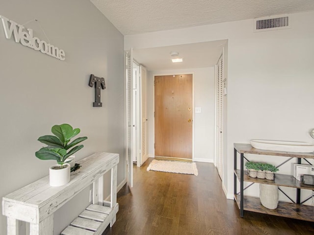 hallway featuring wood finished floors, baseboards, and a textured ceiling