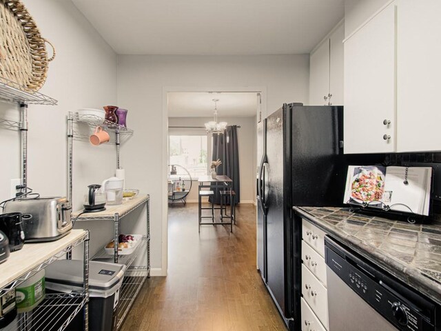 kitchen featuring stainless steel dishwasher, white cabinets, wood finished floors, a chandelier, and tile counters