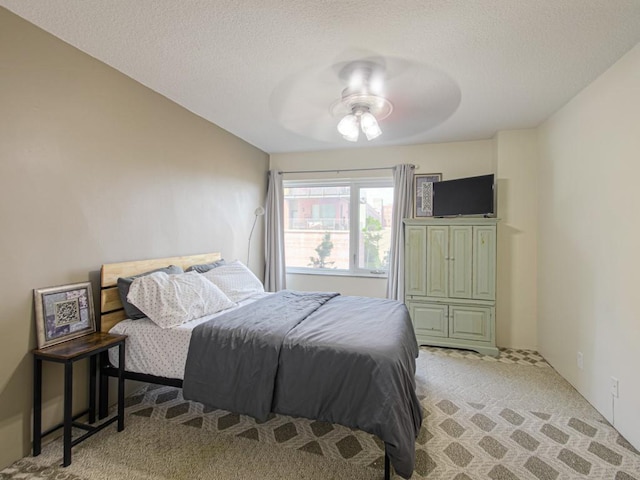 bedroom featuring light colored carpet, ceiling fan, and a textured ceiling