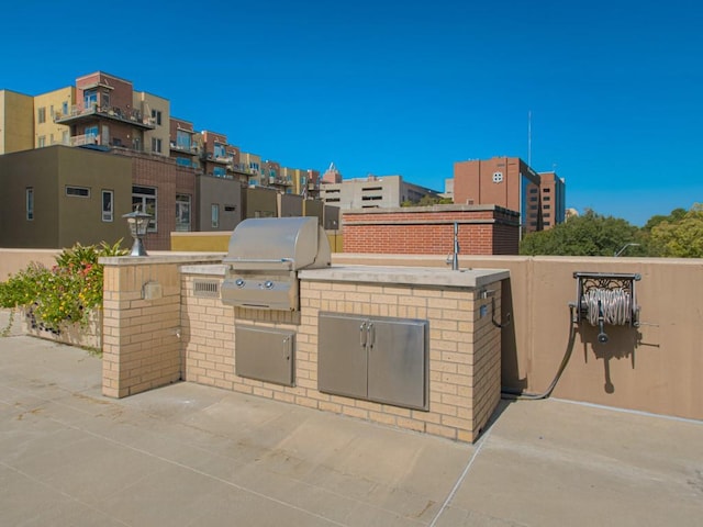 view of patio featuring a grill, an outdoor kitchen, and a residential view