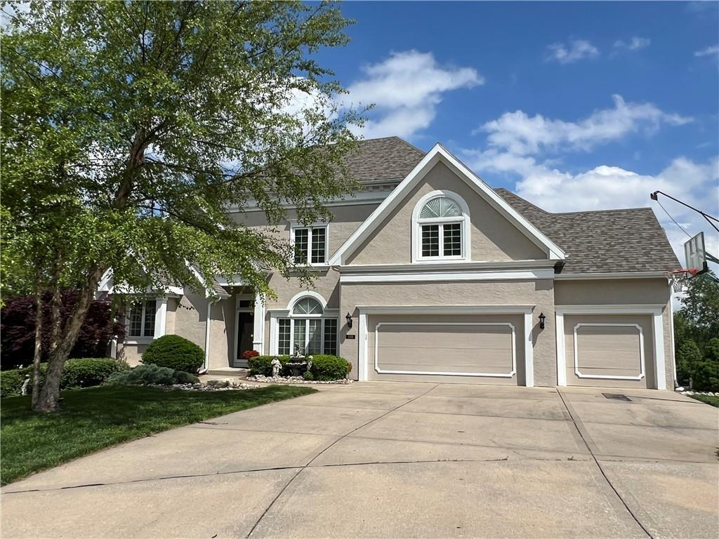 traditional-style home with a garage, stucco siding, and driveway