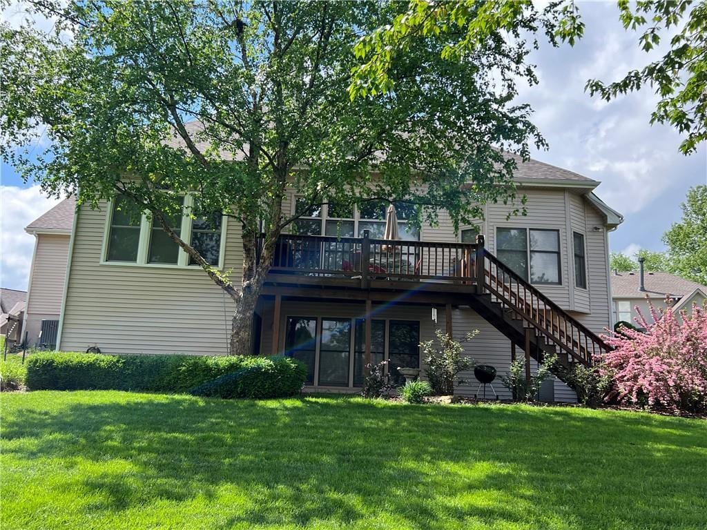 rear view of property featuring a lawn, a deck, and stairway