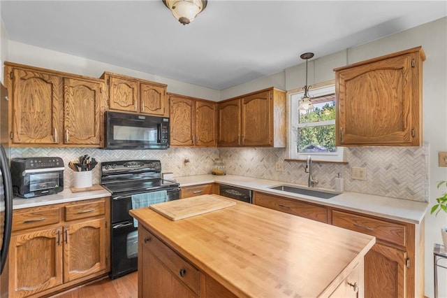 kitchen with black appliances, a sink, butcher block countertops, pendant lighting, and backsplash